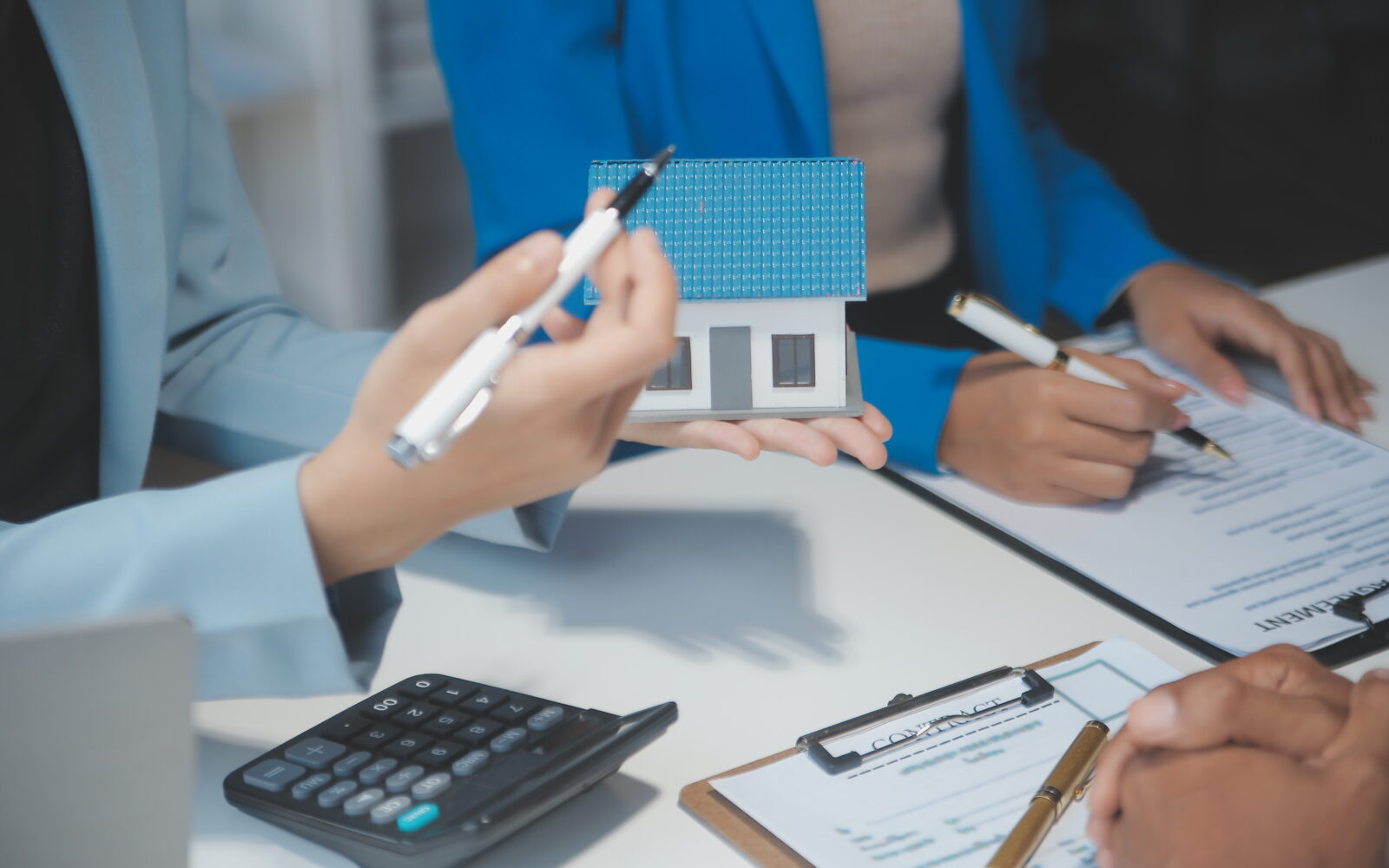 Real estate agent and customer signing contract to buy house, in